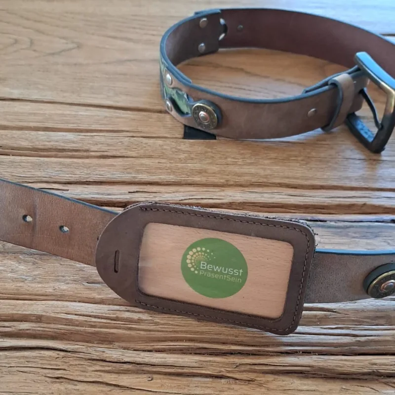 Leder-Anhänger mit Energiekarte BewusstPräsentSein, auf einen Ledergürtel gefädelt, auf einem Holztisch